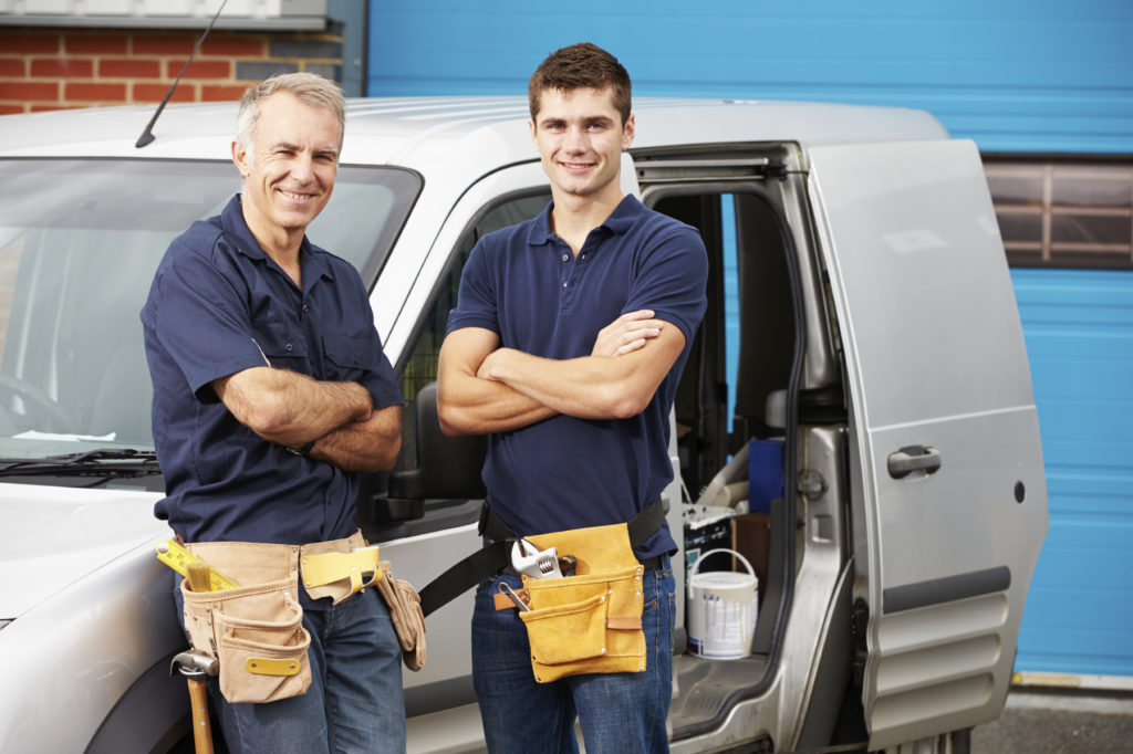 Workers In Family Business Standing Next To Van